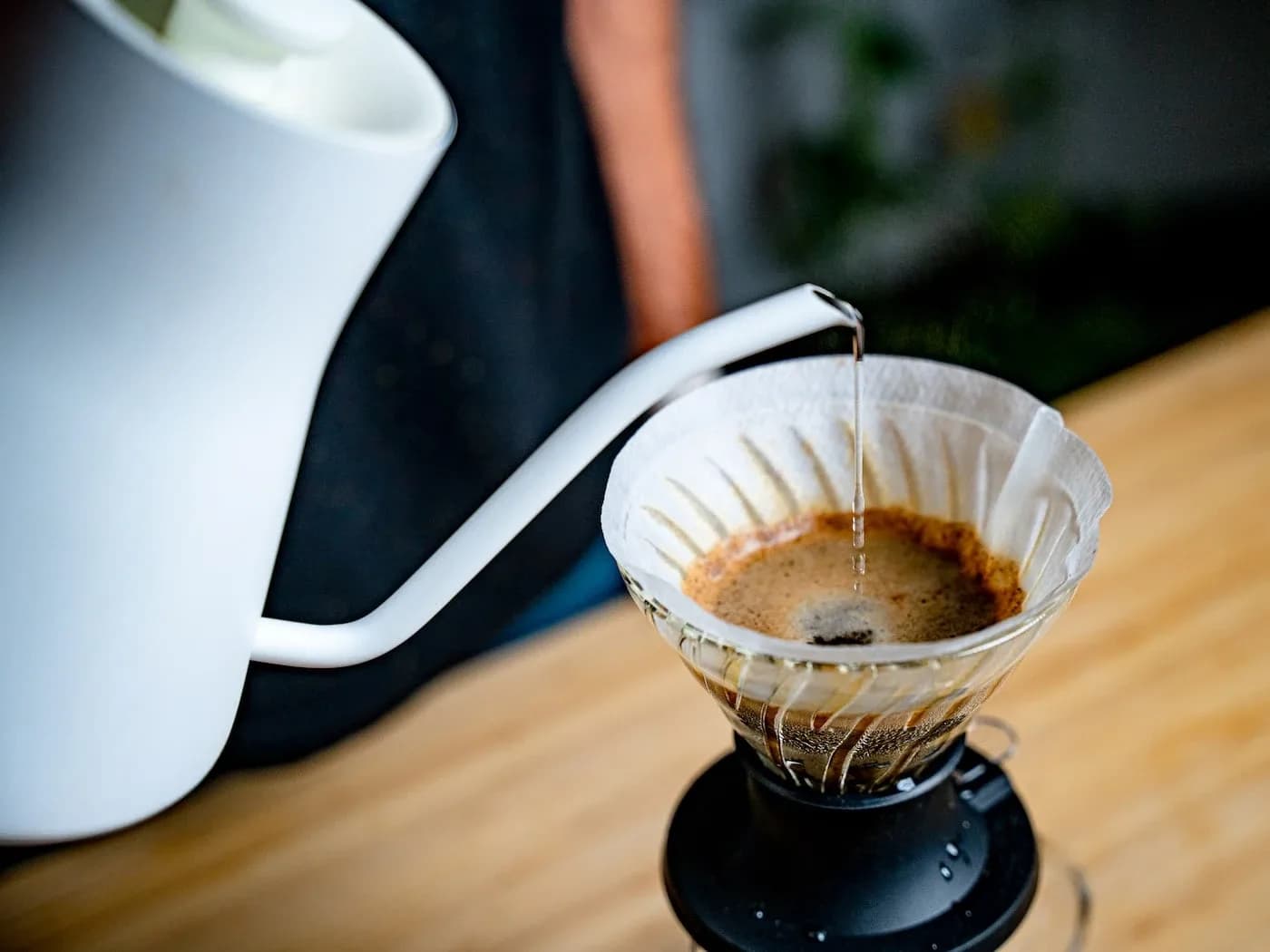Beyaz kettle ile V60'a ince ve yavaş döküş — düz kahve yatağı